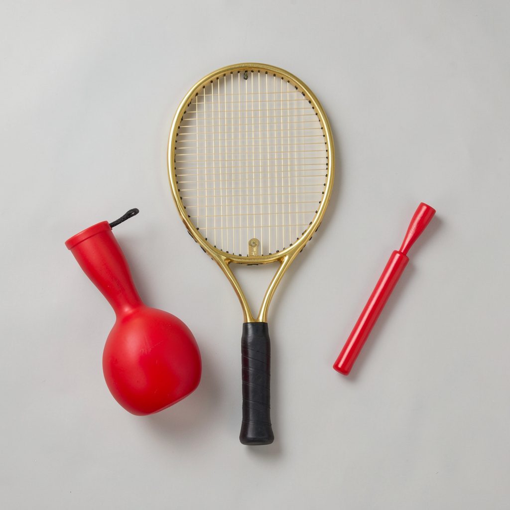 Overhead flat-lay of a gold and black table tennis racket resting on a dark surface with a table tennis ball beside it, sleek and focused mood